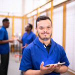 Portrait of special needs employee holding digital tablet in industry